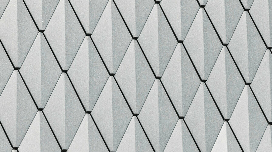 Trapezowa lukarna domu jednorodzinnego w Mechernich, pokryta małymi dachówkami PREFA w kolorze P.10 antracytowym. Dach pokryty jest gontami PREFA DS.19 w tym samym kolorze. Wysokiej jakości aluminiowa okładzina zapewnia odporność na warunki atmosferyczne oraz nowoczesny, estetyczny wygląd.