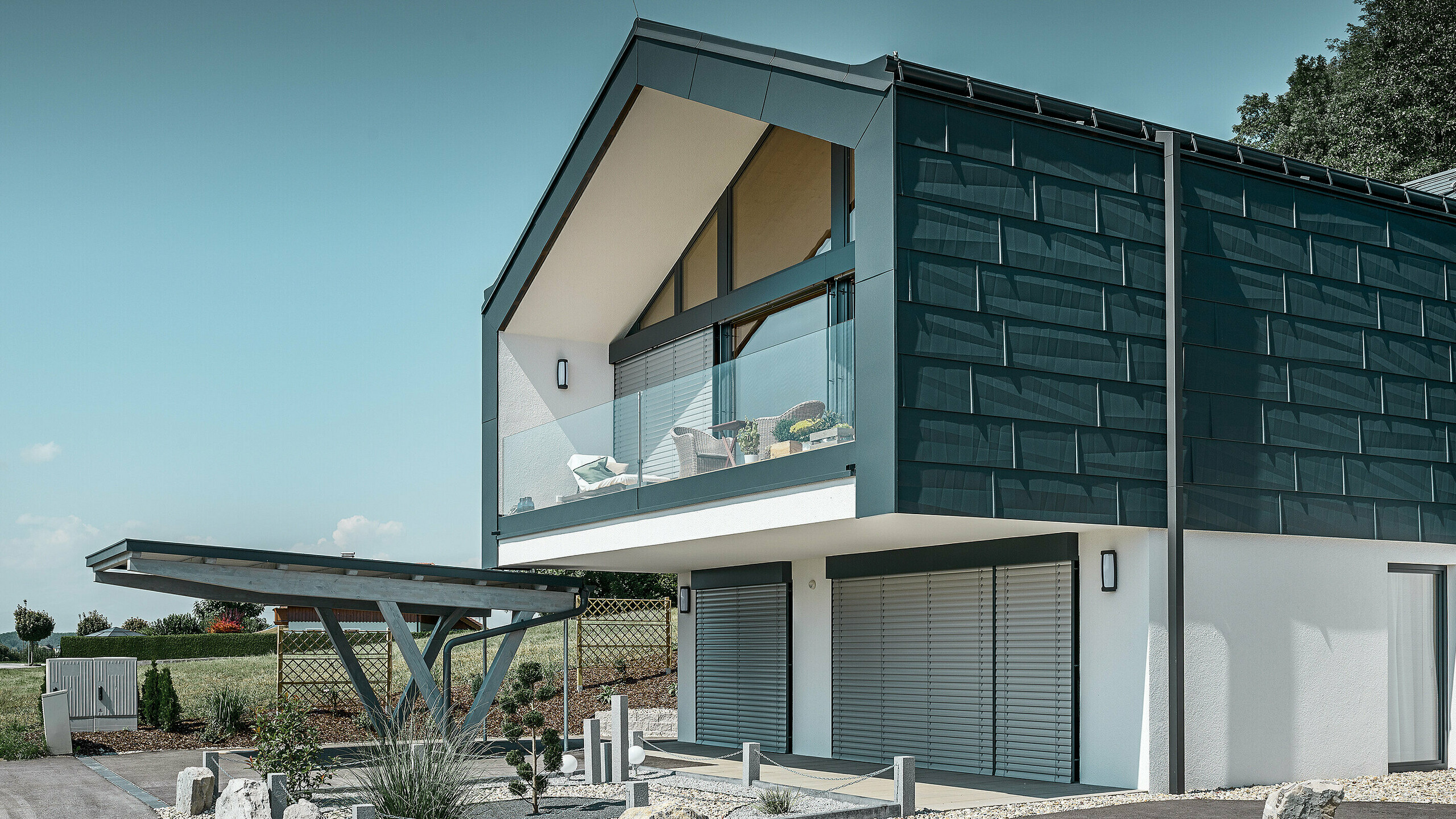 Okładzina elewacyjna piętra z panelem elewacyjnym PREFA FX.12 w kolorze P.10 antracyt. Solidna rura kwadratowa PREFA służy jako rura odpływowa.