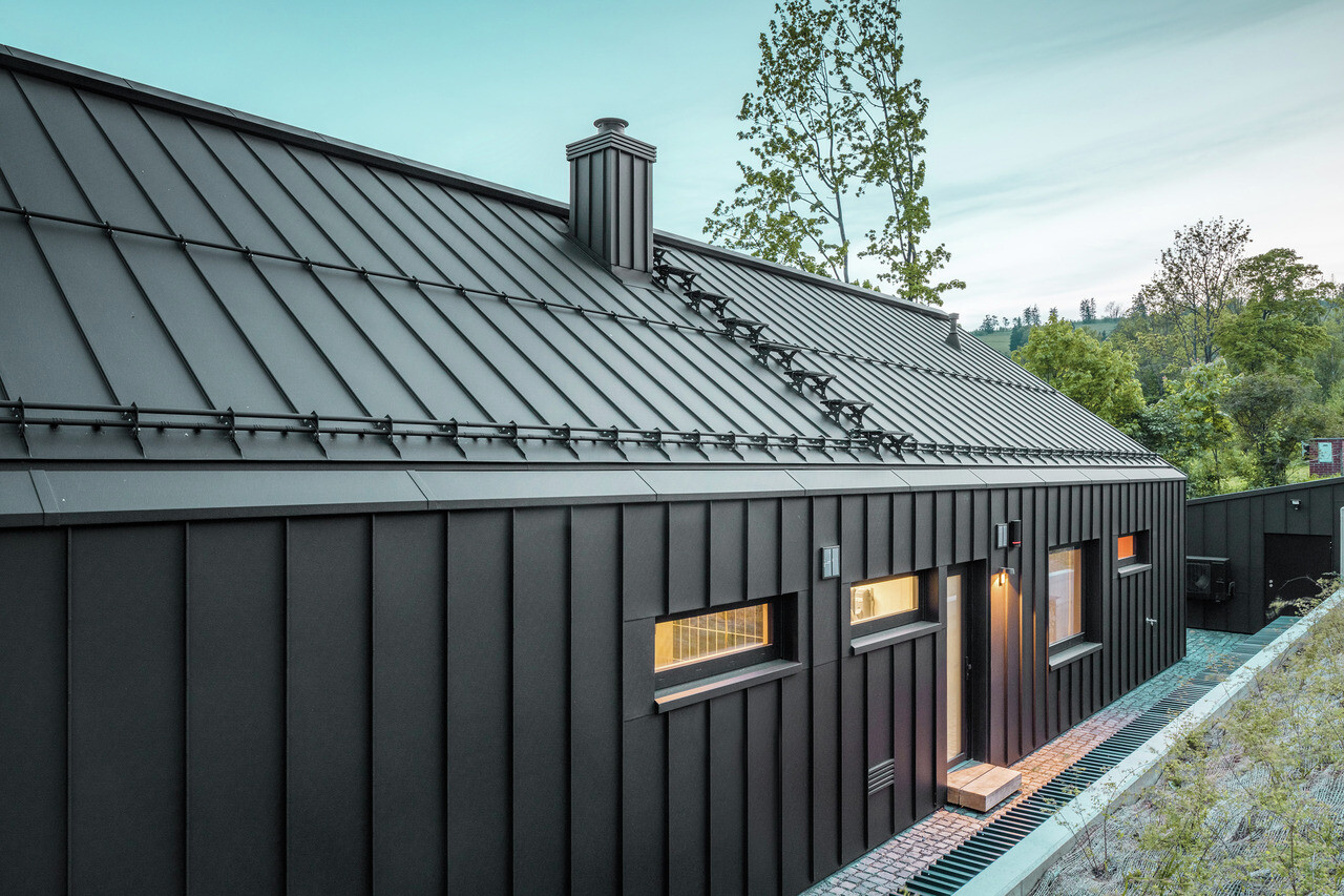 Das Bild zeigt ein Einfamilienhaus mit einem Dach und einer Fassade aus PREFALZ, Farbton P.10 Schwarz.