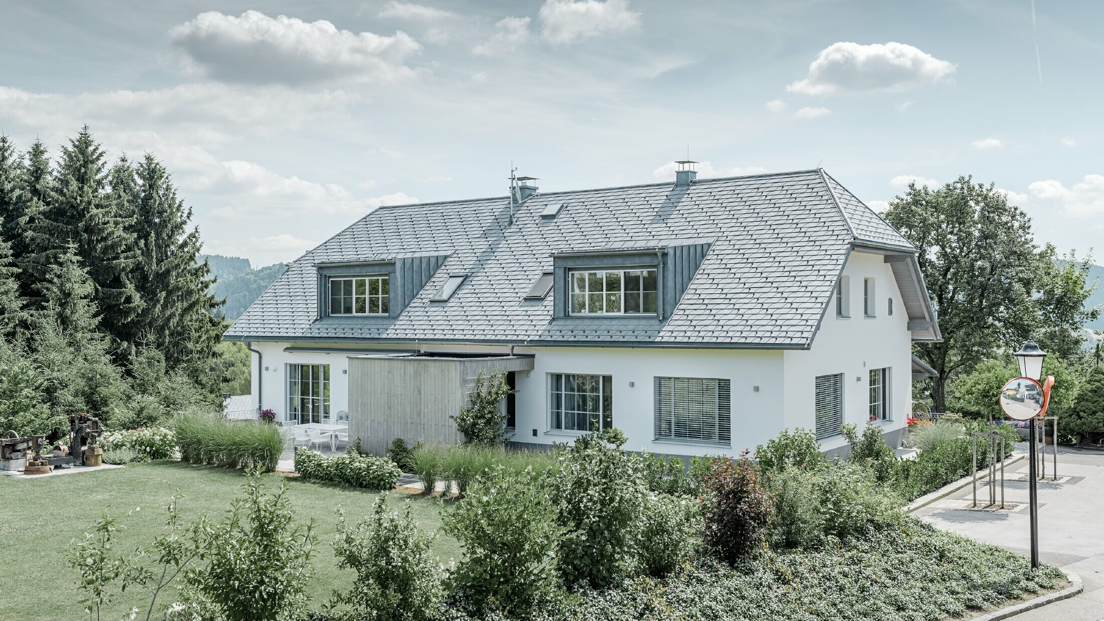 Renowacja dachu czterospadowego z lekkimi dachówkami łupkowymi PREFA w kolorze szarym kamiennym z dwoma lukarnami.