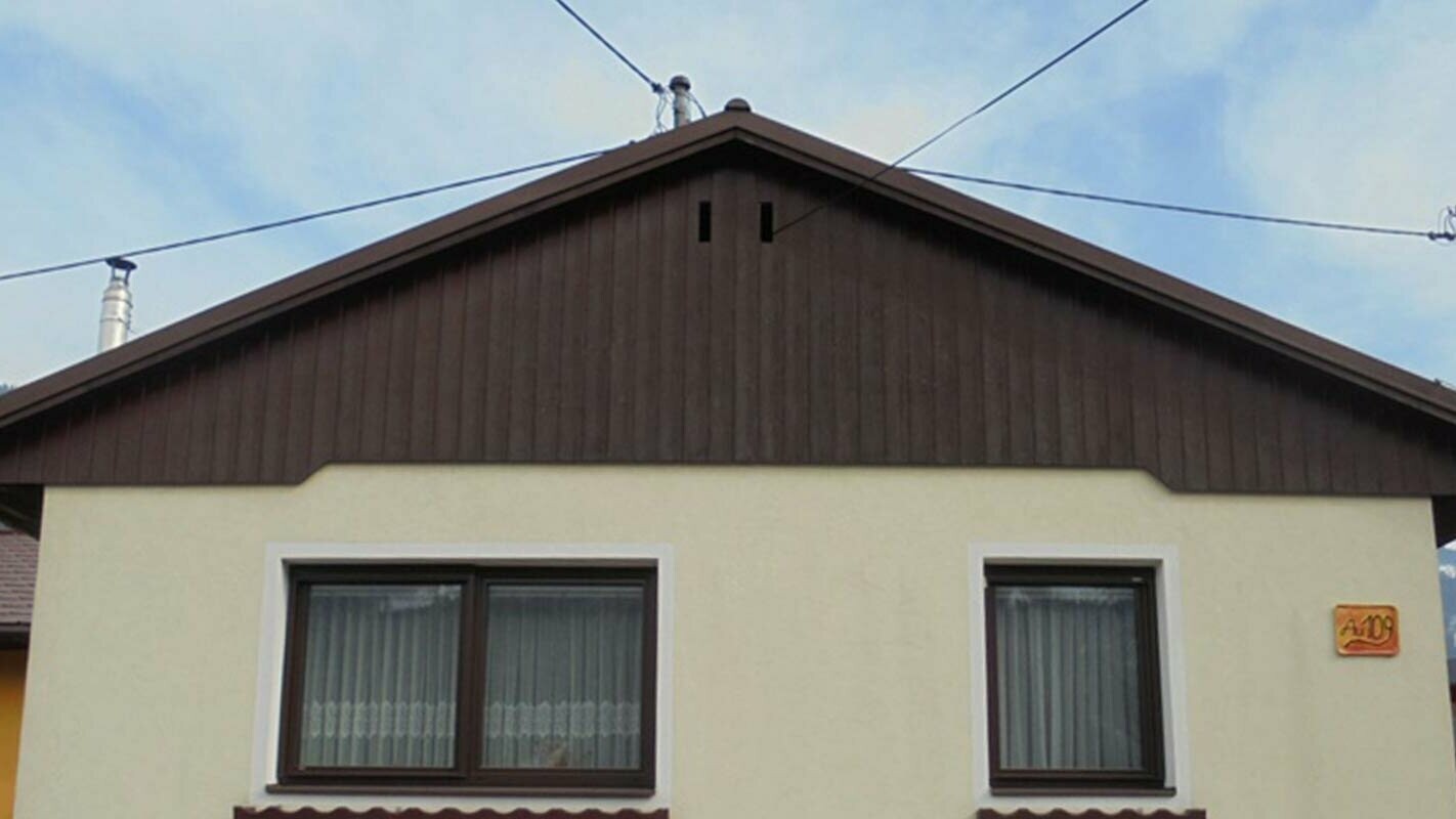 Przed modernizacją elewacji ściany szczytowej z sidingami PREFA, żółta elewacja tynkowa i zwietrzałe drewno