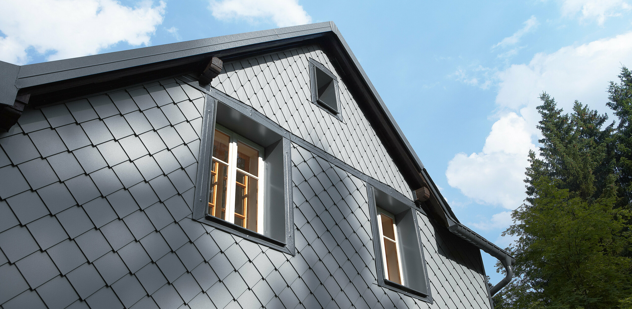 Strona wystawiona na działanie czynników atmosferycznych pokryta rombami ściennymi 20 × 20 i małymi rombami na elewacji PREFA.