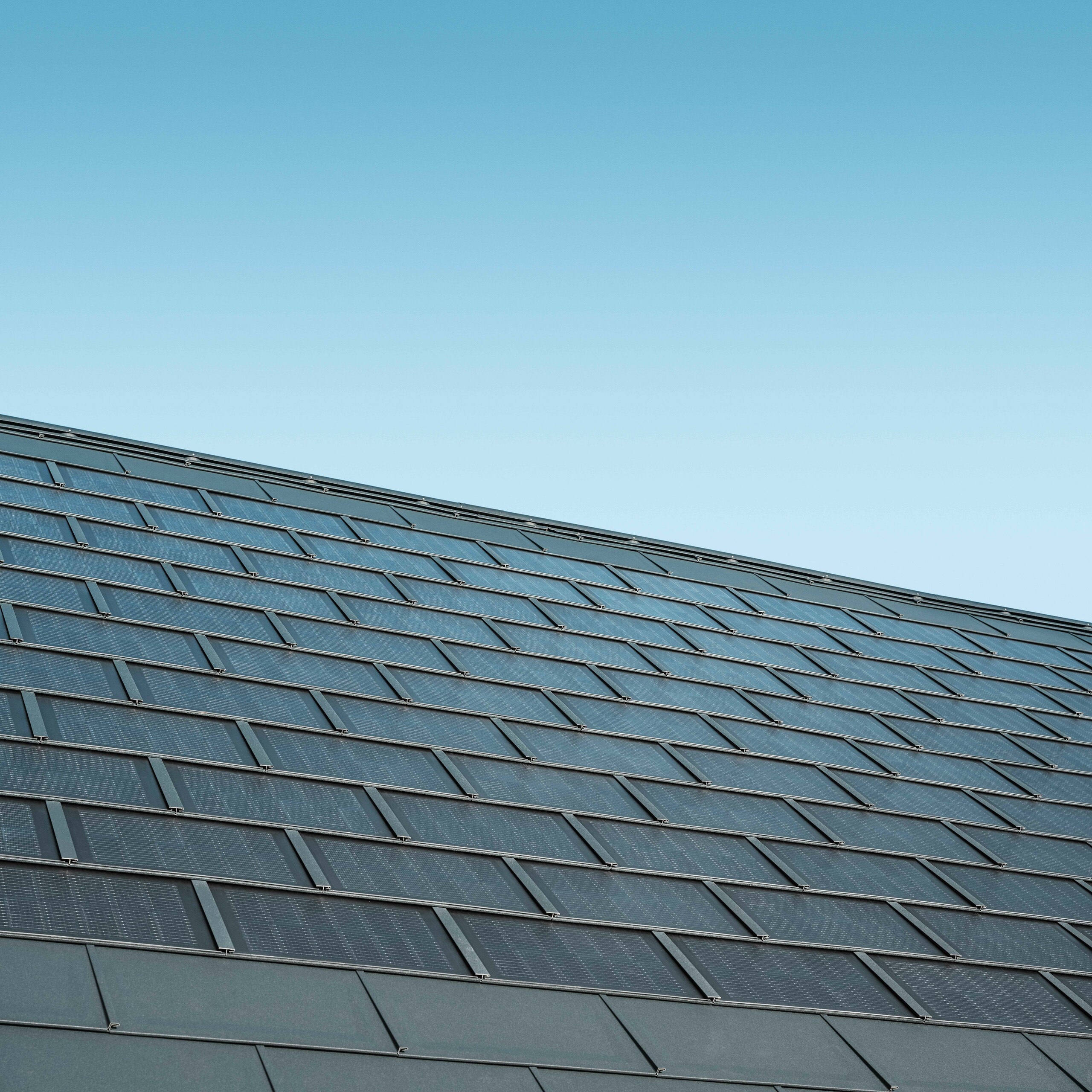 Zdjęcie ułożonej połaci z dachówka solarna w kolorze antracytowym w połączeniu z dachówką klasyczną R.16