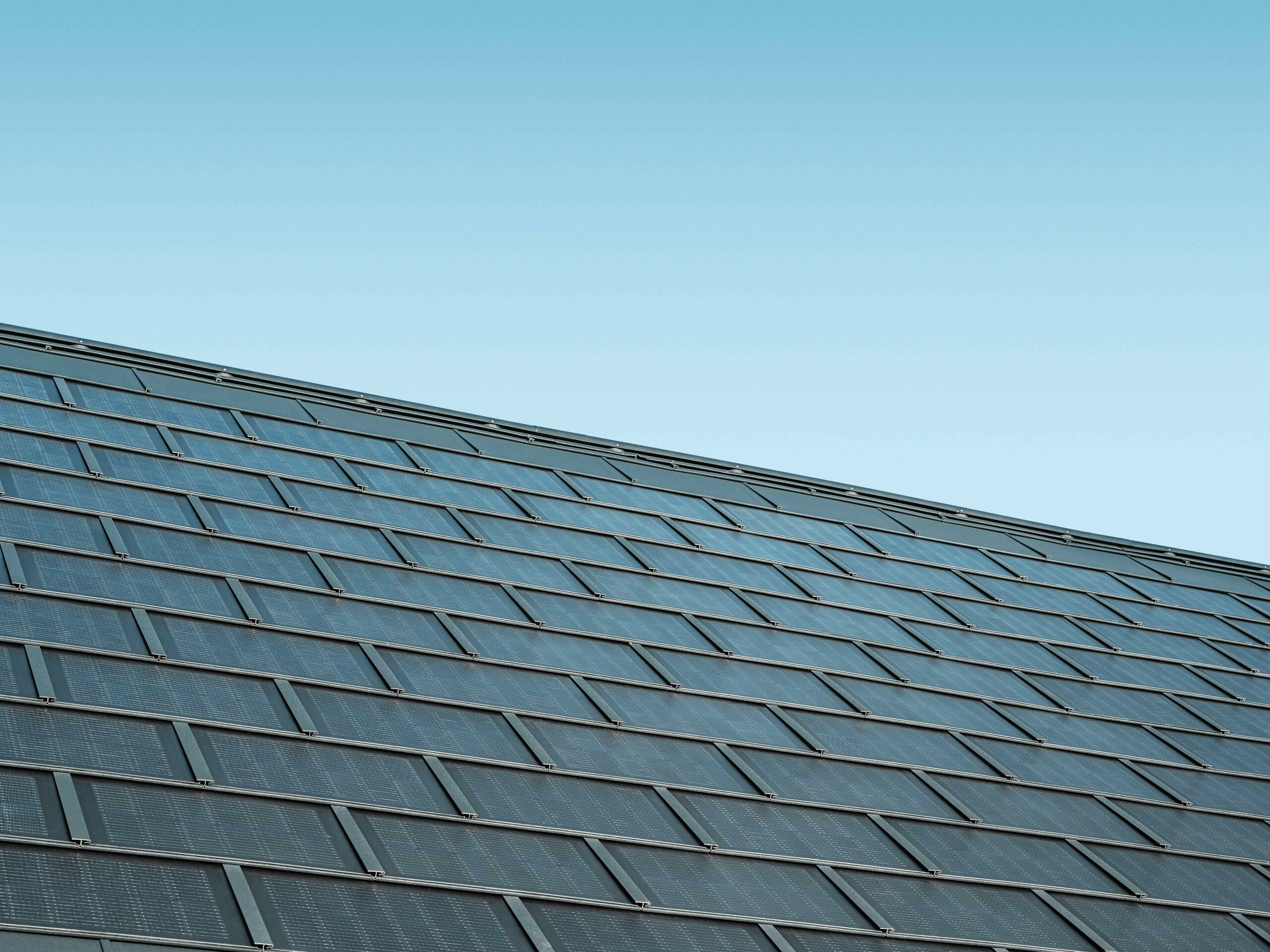 Zdjęcie ułożonej połaci z dachówka solarna w kolorze antracytowym w połączeniu z dachówką klasyczną R.16