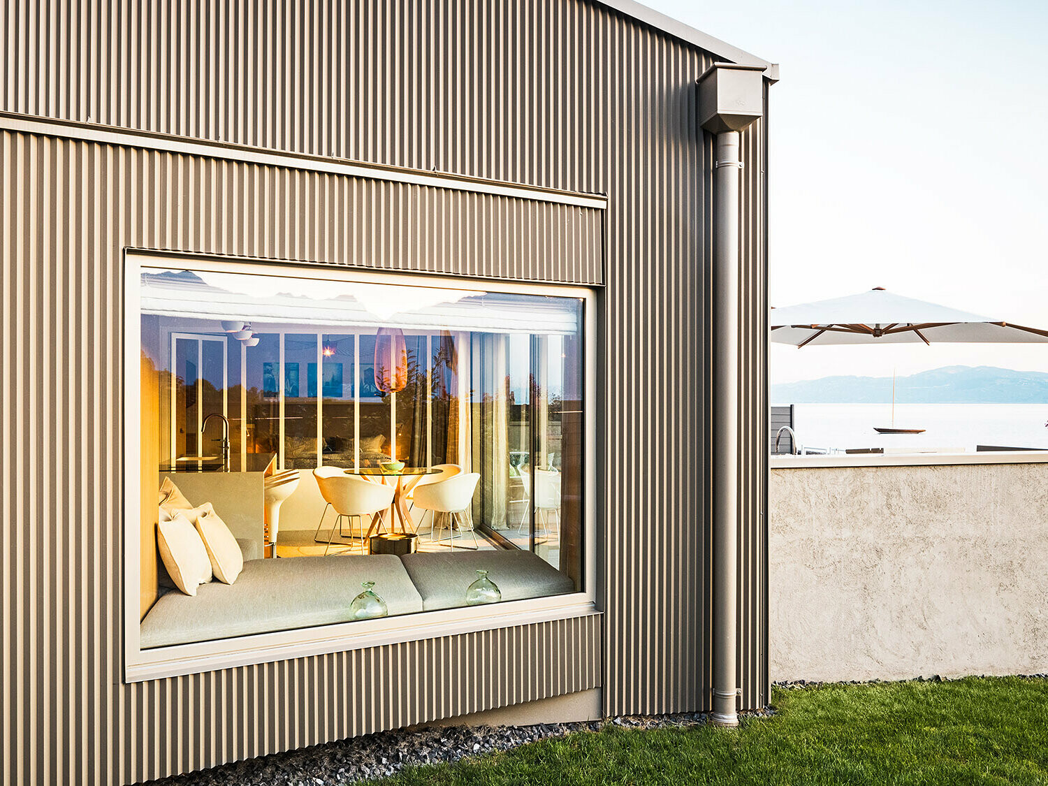 Widok z boku budynku z trójkątną elewacją aluminiową, widać część oświetlonego wnętrza.