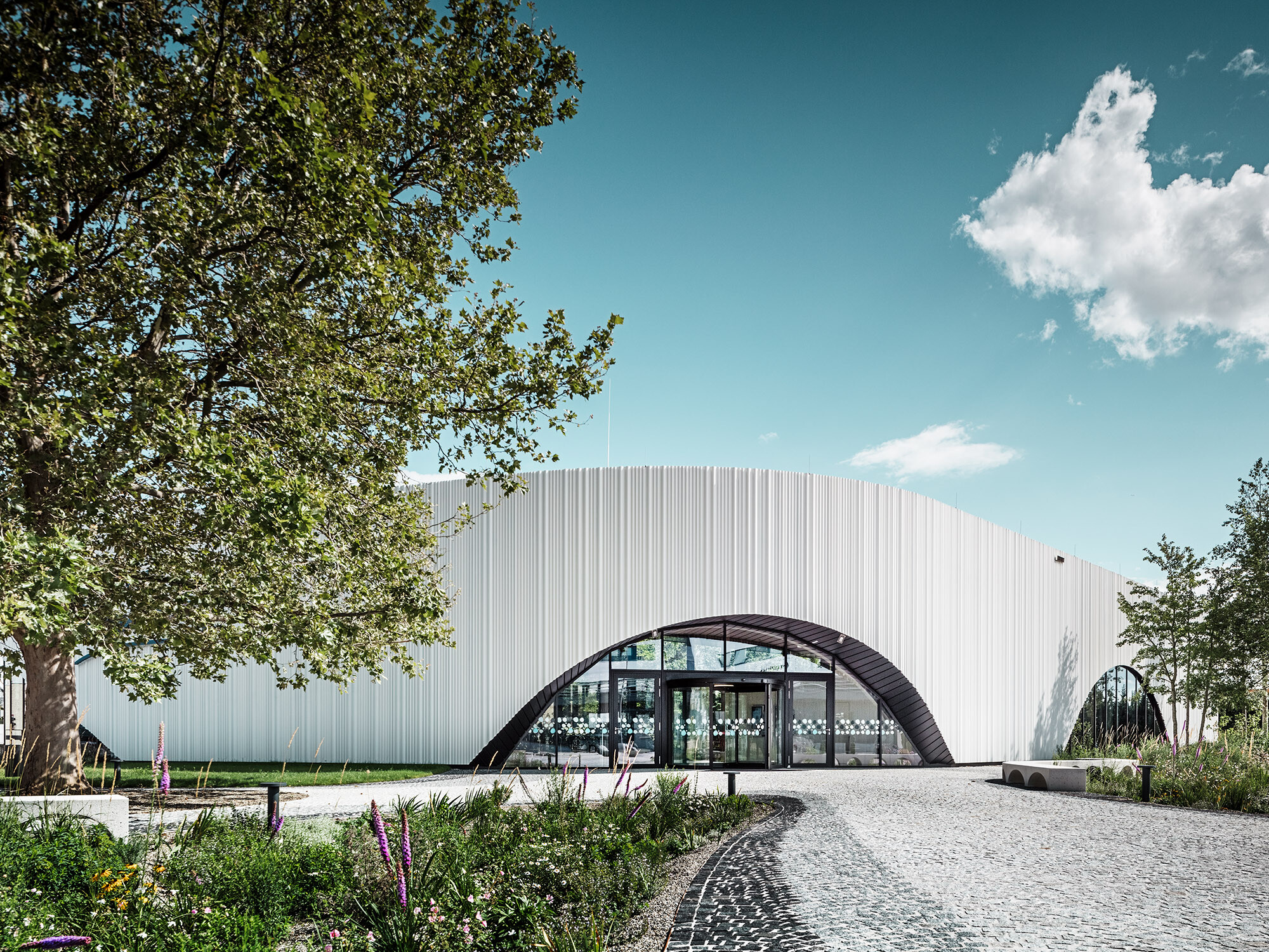 Widok ogólny restauracji Walters z jednym z półokrągłych okien pośród zieleni.