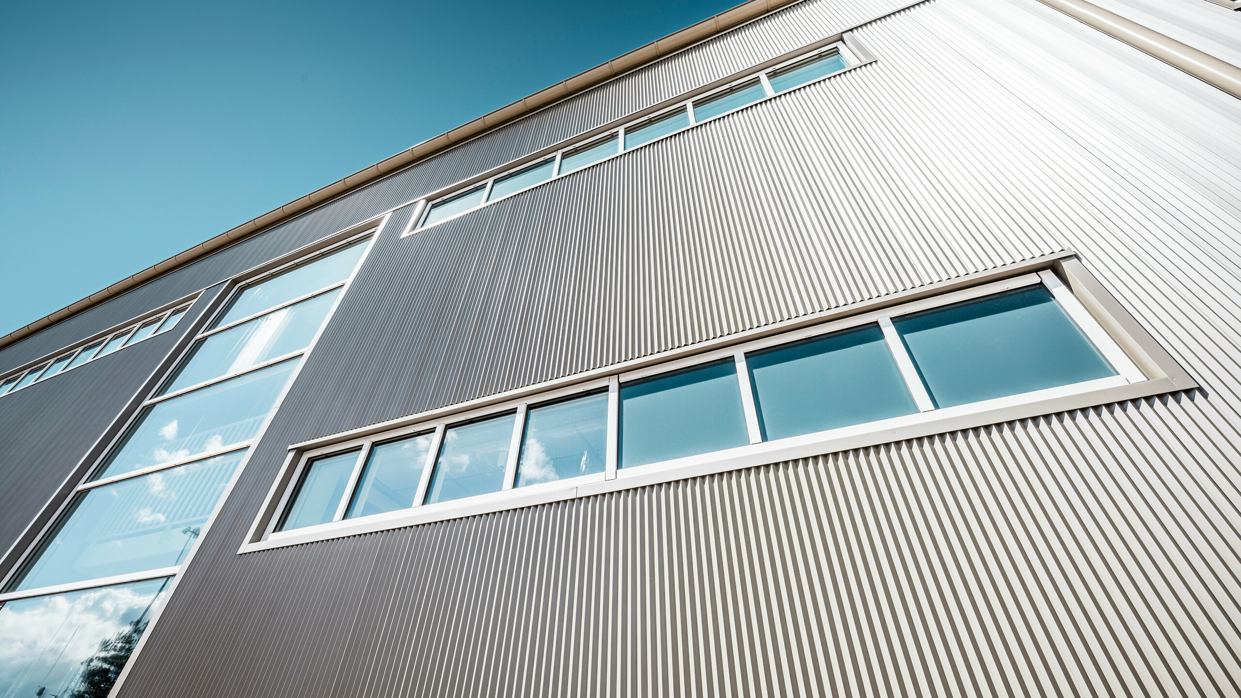 Außenansicht der Park Arena in Värnamo, Schweden, mit einer modernen PREFA Fassade in Bronze. Die Zackenprofile aus Aluminium schaffen markante Licht- und Schatteneffekte. Die eingebetteten Fenster fügen sich harmonisch in die präzise verarbeitete Fassade ein, die für Langlebigkeit, Widerstandsfähigkeit und zeitgemäßes Design steht.