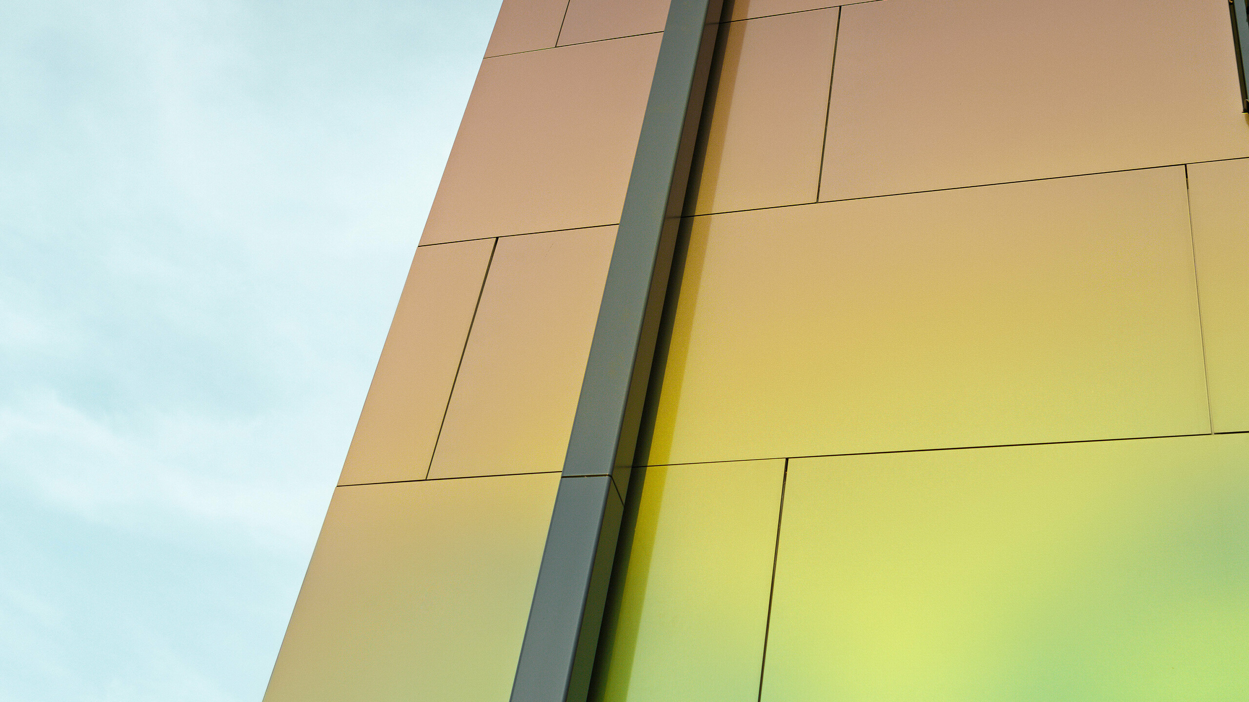 Krawędź nowoczesnego domu jednorodzinnego z nowoczesną rurą spustową PREFA do odprowadzania wody z płaskiego dachu. Elewacja jest pokryta aluminiową płytą kompozytową w połyskującym kolorze „spring lake”.