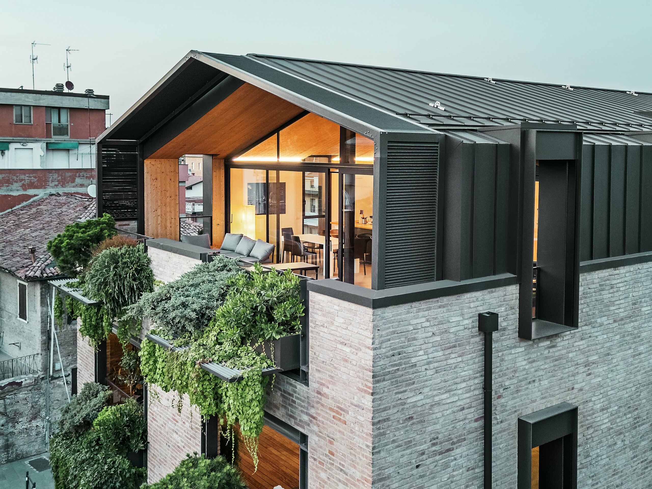 Nowoczesny budynek mieszkalny we Włoszech z dachem aluminiowym PREFALZ w kolorze P.10 orzechowym, dużymi powierzchniami szklanymi, zieloną elewacją i dachówką – udane połączenie zrównoważonego rozwoju i współczesnej architektury.