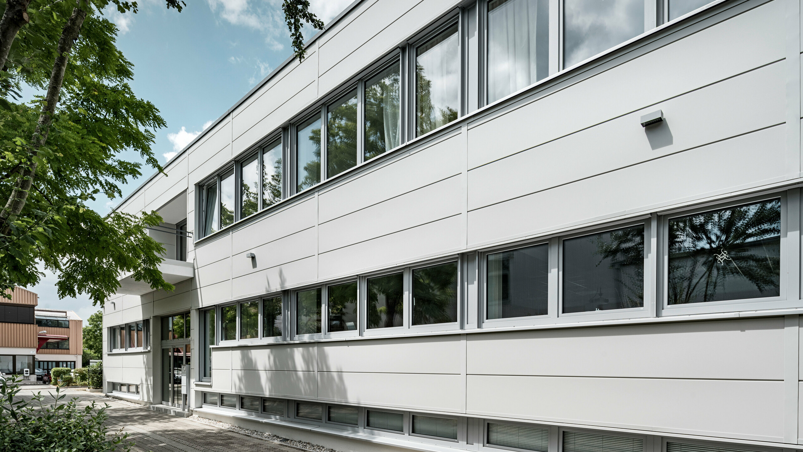 Großformatige PREFA Sidings umhüllen ein Firmengebäude in Oberschleißheim (Deutschland). Die extrabreiten Fassadenelemente aus Aluminium sind in der Farbe Prefaweiß gehalten.