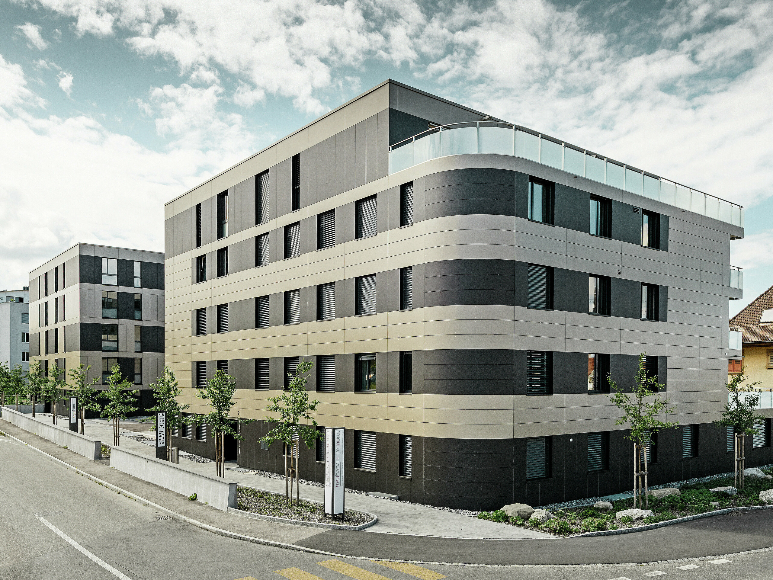 Osiedle domów mieszkalnych w kształcie kostek z elewacją aluminiową w kolorze brązu z czarno-szarymi elementami