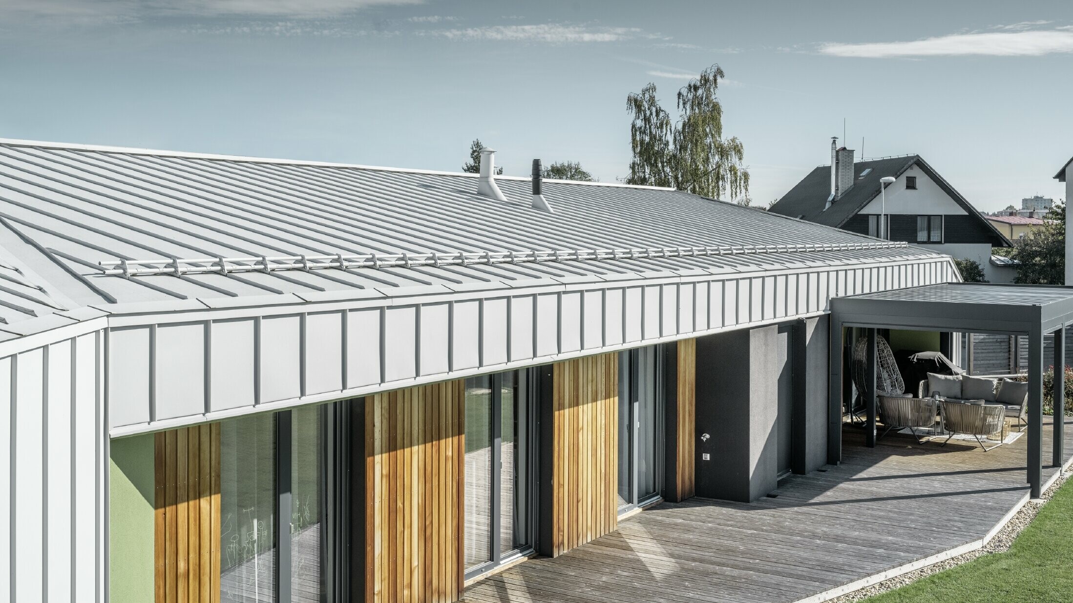 Bungalow z dachem PREFALZ i elewacją w kolorze białym PREFA oraz drewnianym tarasem