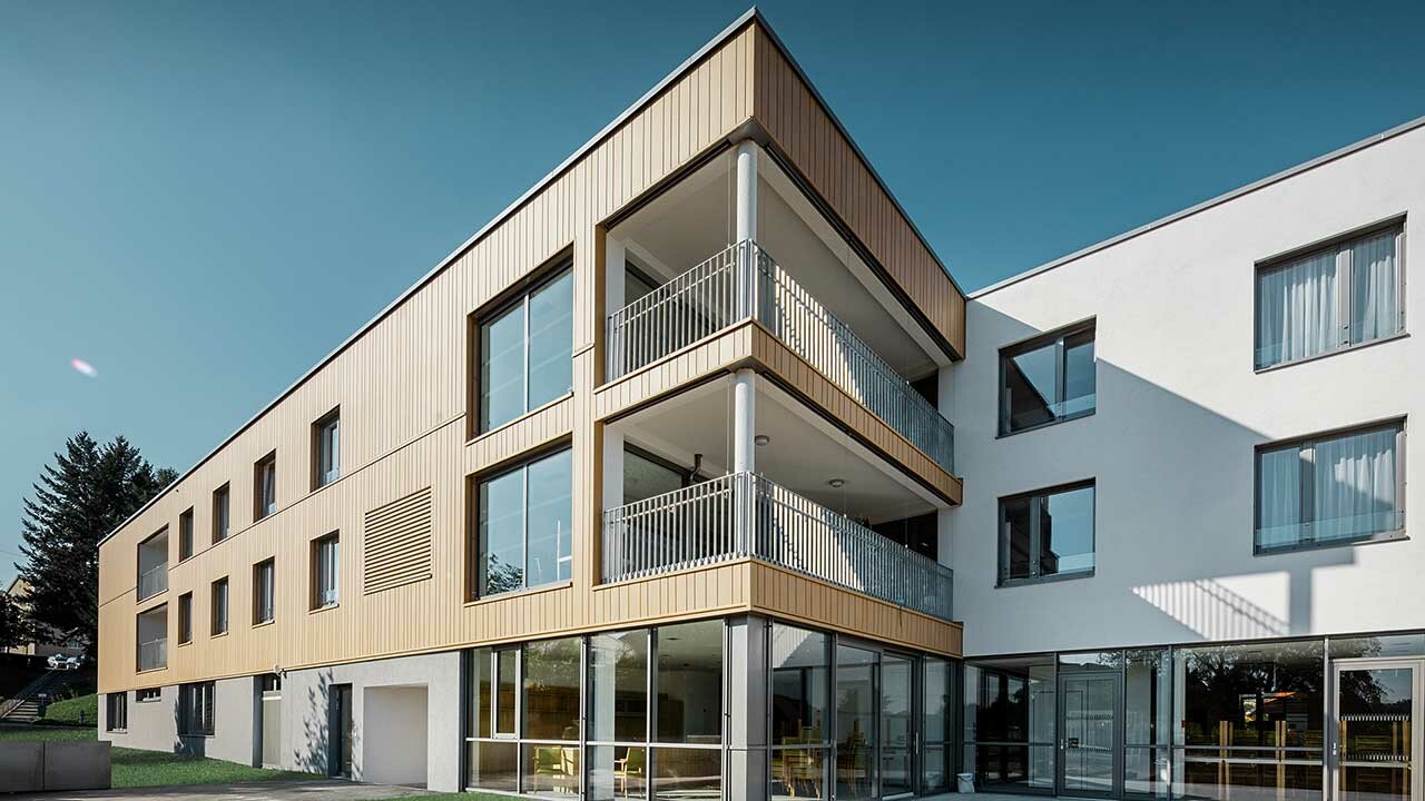 Dom seniora z płaskim dachem i sidingiem elewacyjnym PREFA w kolorze piaskowego brązu