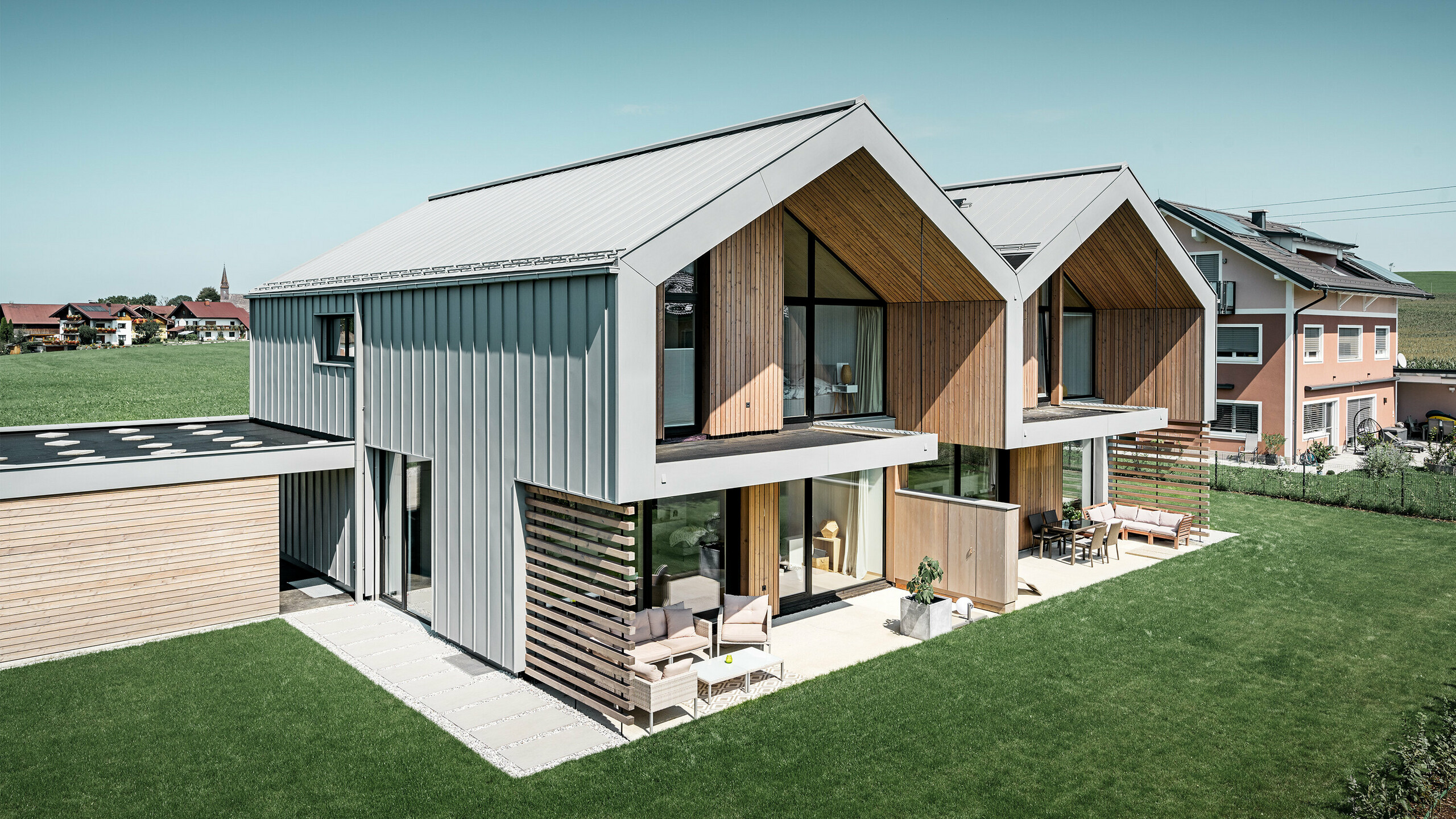 Nowoczesne bliźniaki z dachem i elewacją PREFALZ, w kolorze szarej patyny, łącznie z rurą kwadratową